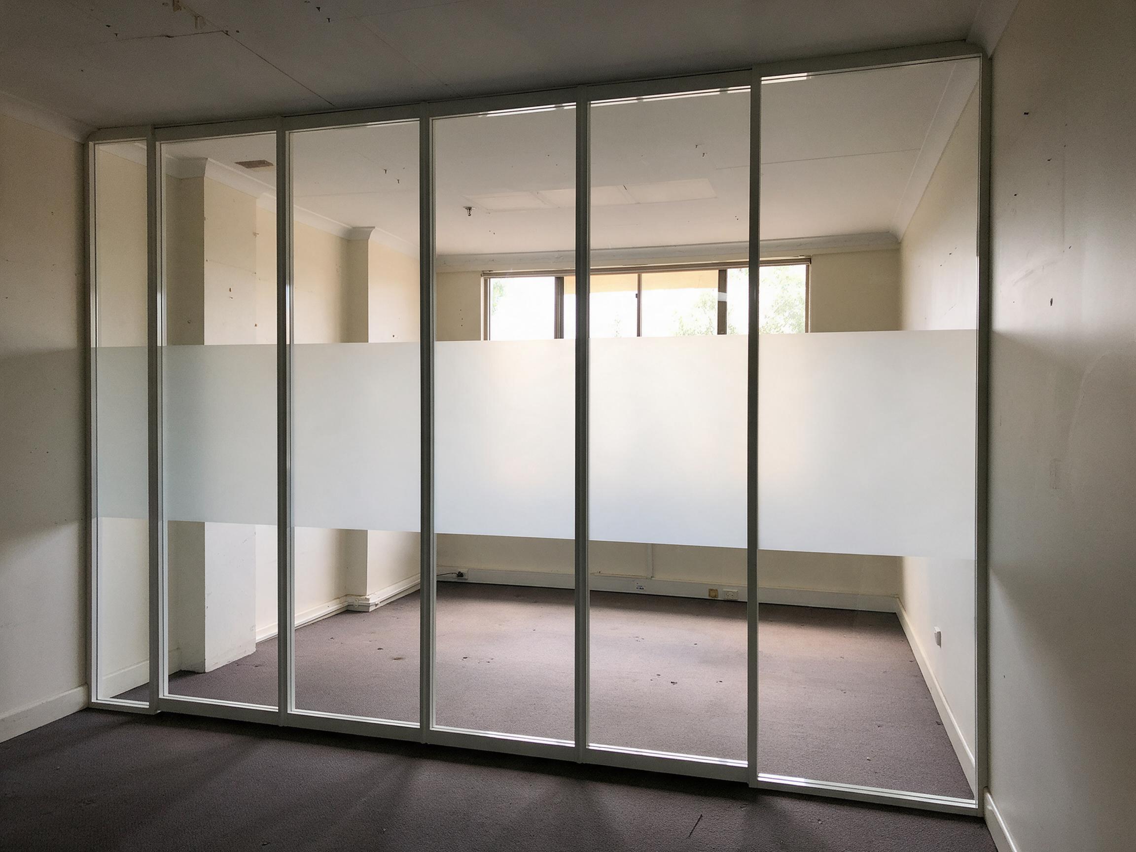 A glazed office partition with a frosted band across it, the band level and continuous through every panel joint