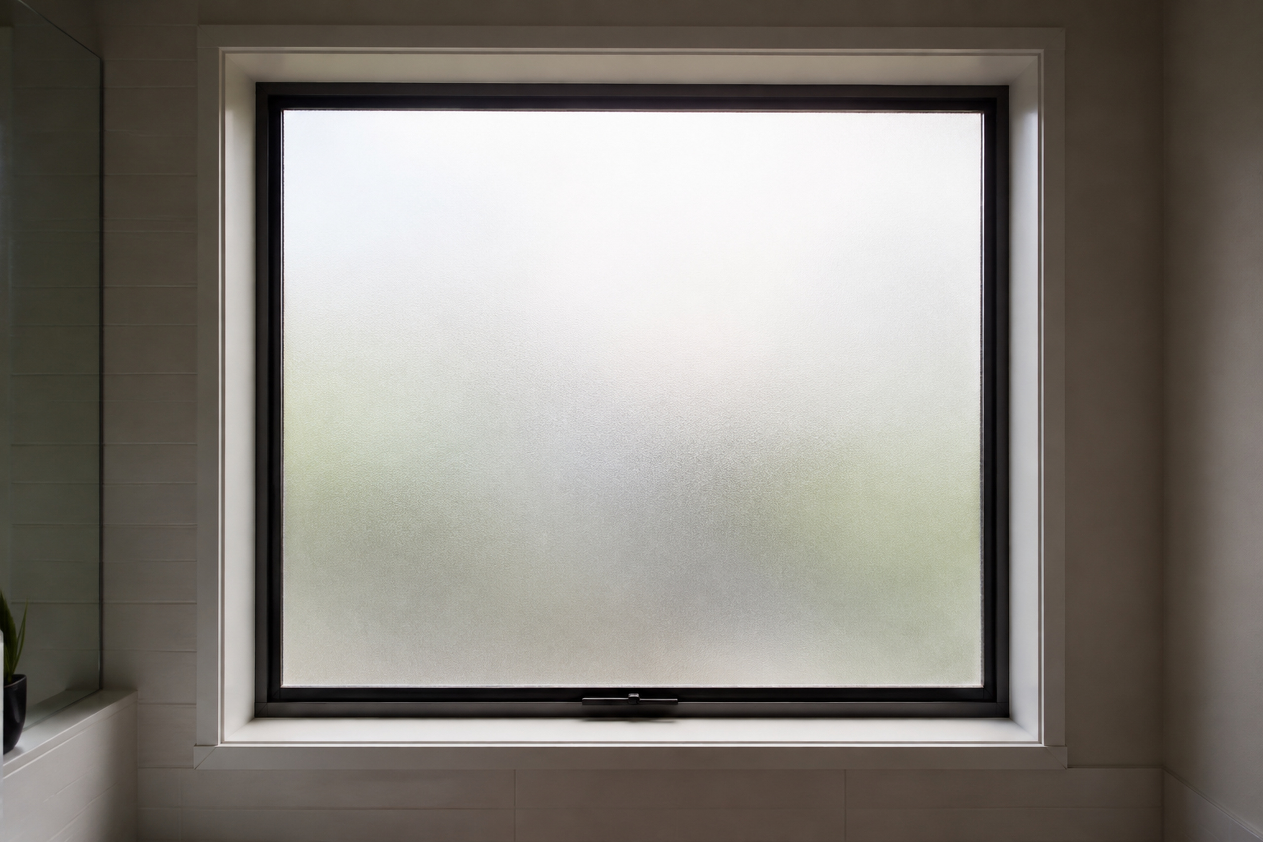 A bathroom window with frosted film across the glass, the garden beyond reduced to soft tone and the daylight still entering the room