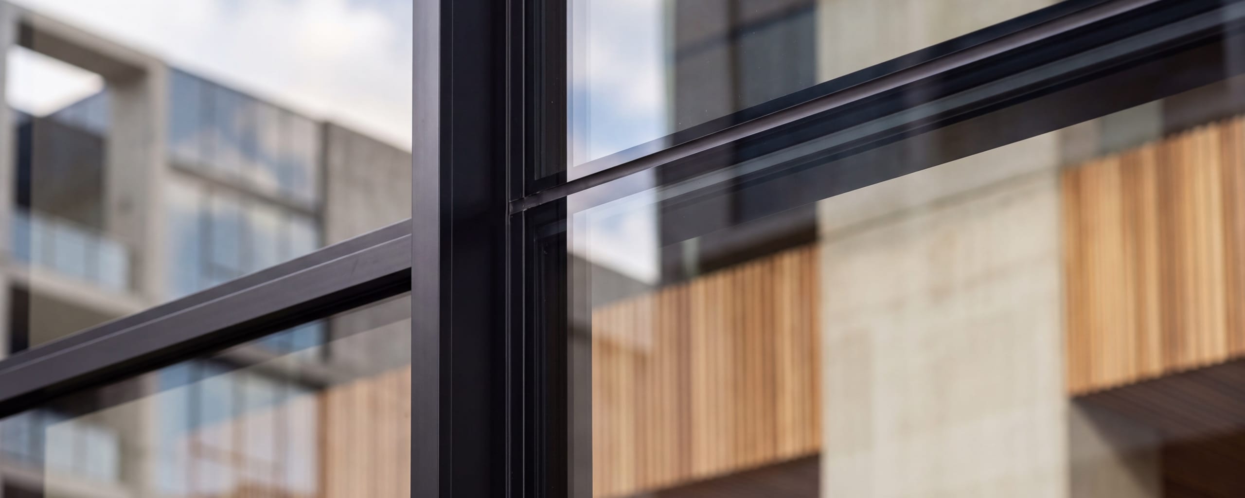 A close detail of glazing where a pane meets its frame, with soft daylight across the glass